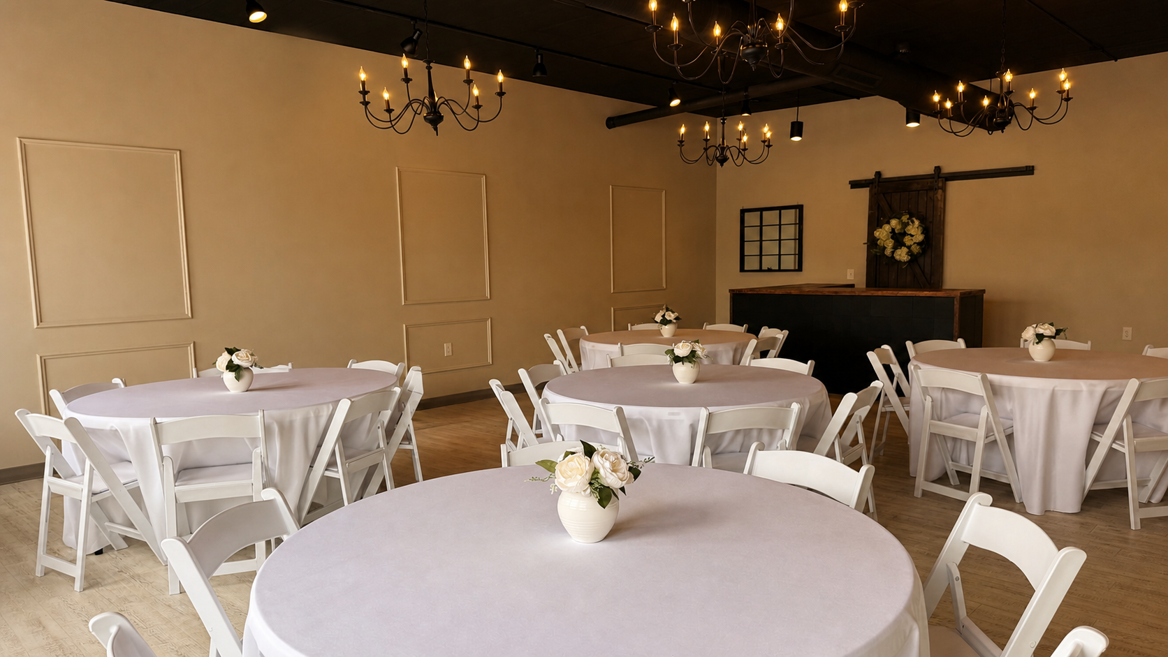 The Gathering event room prepared with ivory linens and warm chandelier lighting